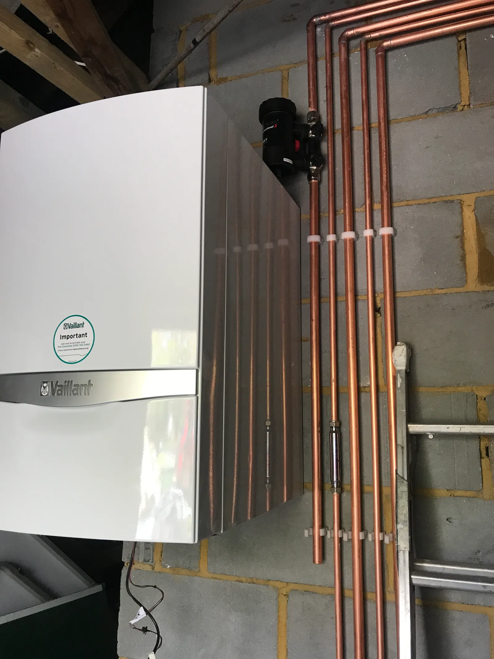 A Vaillant boiler fitted by On Heating, with a magnetic system filter on the return and parallel copper pipework clipped neatly to the wall above it.